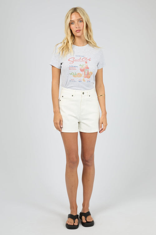 Woman wearing a graphic t-shirt and white shorts on a plain background