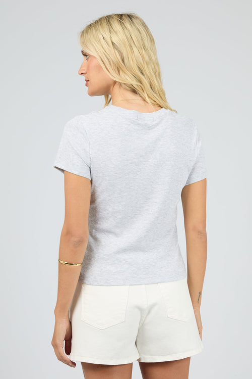 Woman wearing a light gray t-shirt and white shorts on a plain background