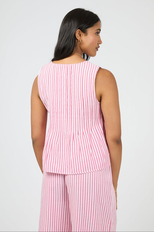 Woman wearing a pink and white striped sleeveless top and pants on a light gray background