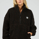 Person wearing a black fleece pullover with a logo on a gray background