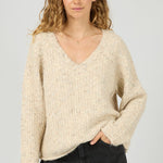 Woman wearing a beige sweater and black pants on a white background
