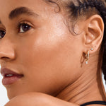 Close-up of a woman with braided hair wearing earrings on a white background