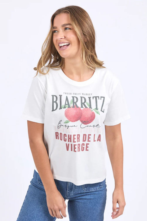 Woman wears a white apple print shirt and blue denim