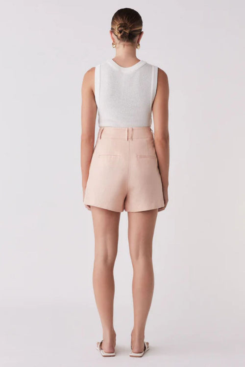 Woman wearing pink shorts and a white tank top