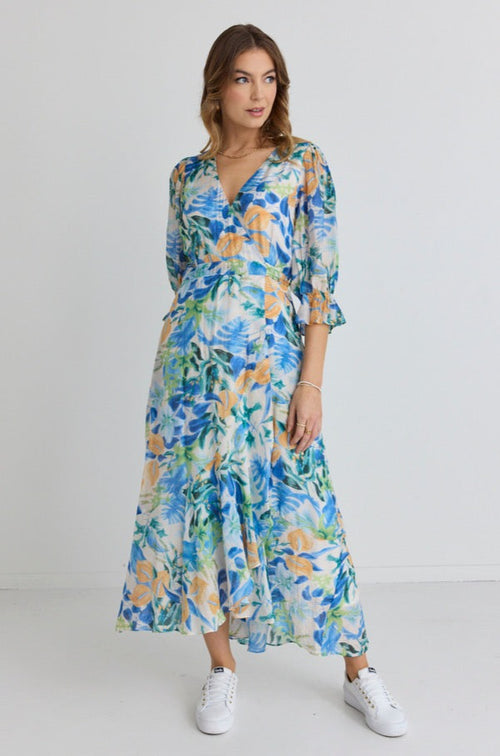 model wears and blue and orange floral maxi dress with white sneakers