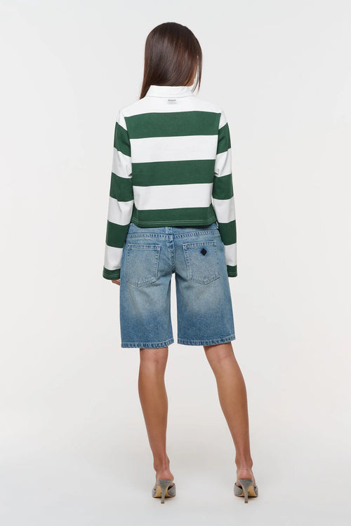 A woman shown from the back wearing a green and white horizontally striped long-sleeve top and light blue denim shorts, standing against a plain white studio background.