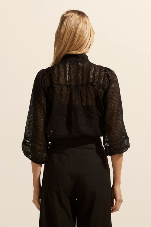 model wears a black blouse with black pants