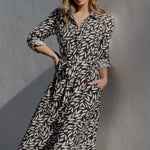 Woman in a patterned dress standing against a plain wall