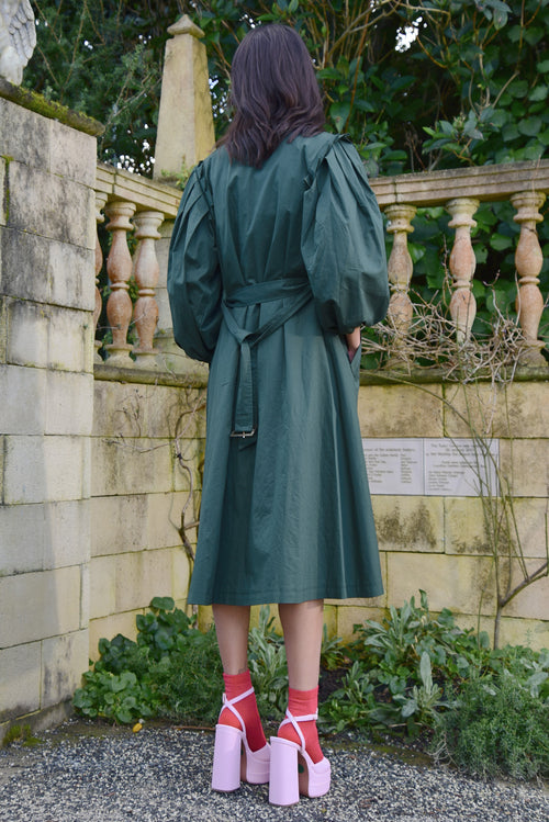 Model wears a green trench coat with a floral dress