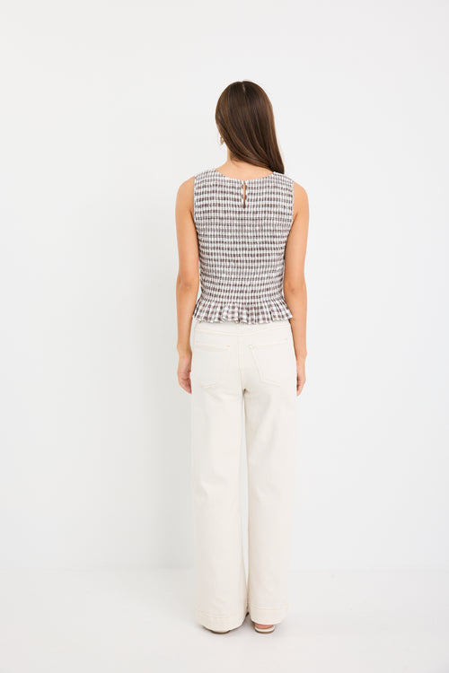 Chocolate gingham sleeveless shell top with frill hem, styled with cream jeans
