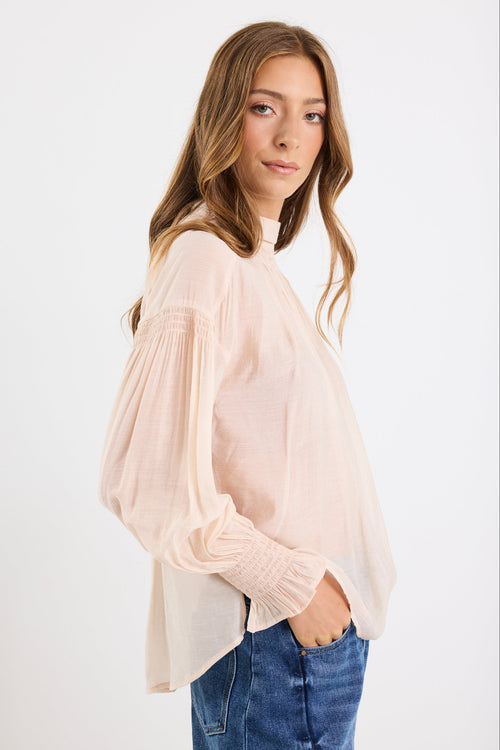 Woman wearing a light pink blouse and blue jeans on a white background