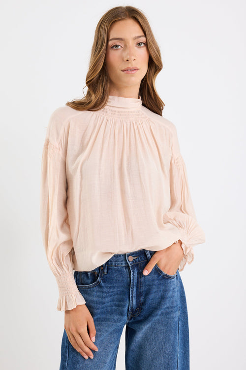 Woman wearing a beige blouse and blue jeans on a white background