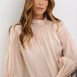 Woman wearing a beige blouse against a white background