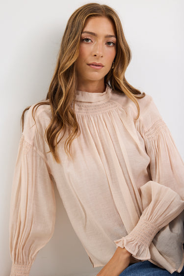 Woman wearing a beige blouse against a white background