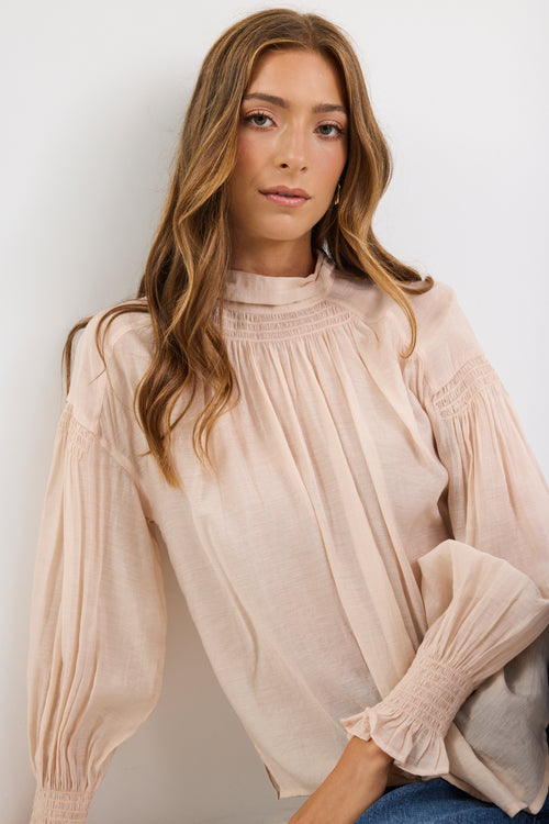 Woman wearing a beige blouse against a white background
