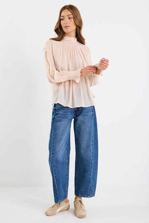 Woman wearing a beige blouse and blue jeans on a white background