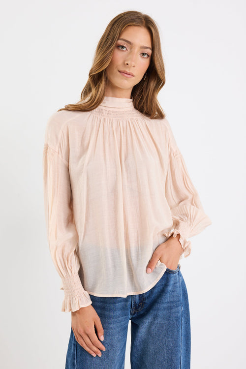 Woman wearing a beige blouse and blue jeans on a white background