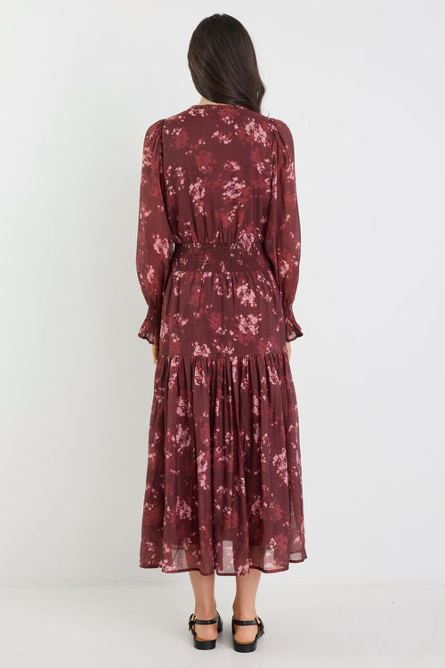 Woman wearing a burgundy floral dress on a white background