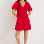 Woman wearing a red dress with ruffled sleeves against a white background