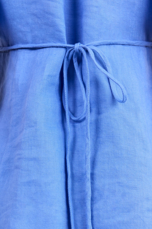 Close-up of a blue linen dress with a matching fabric tie belt at the waist.