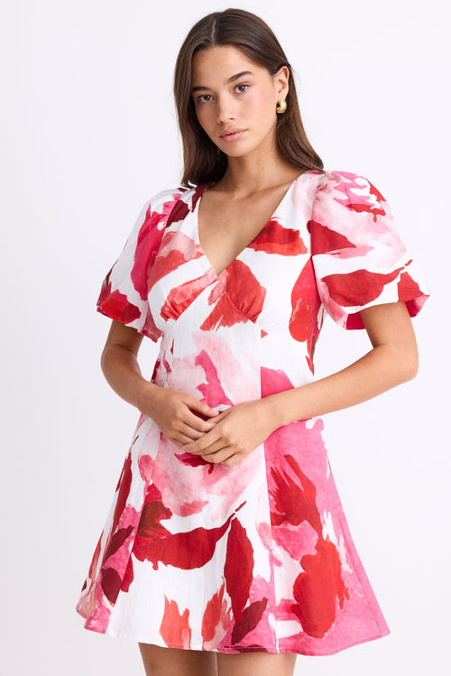Woman wearing a pink and red floral dress on a white background