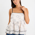 model wears a white floral tank top with blue jeans