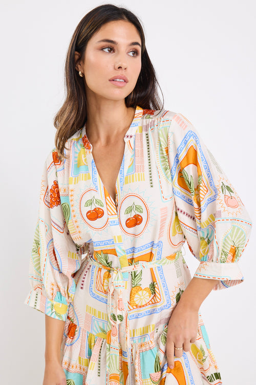 model wears a cream fruit print mini dress