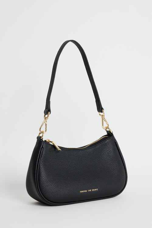 A black pebbled leather crescent-shaped shoulder bag with gold-tone hardware and a small gold logo on the front, photographed on a light gray studio background.