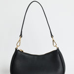 A black pebbled leather crescent-shaped shoulder bag with gold-tone hardware and a small gold logo on the front, photographed against a light gray studio background.