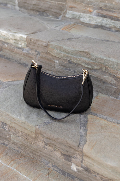 Black handbag with gold accents on stone steps