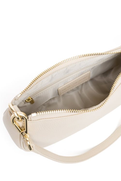 Close-up of a cream-colored leather shoulder bag with gold-tone hardware, showing the interior lining and zipper compartment against a white background.