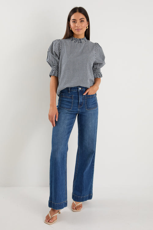 model wearing gingham shirred top and blue jeans. 