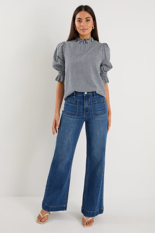 model wearing gingham shirred top and blue jeans. 