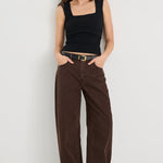 Woman wearing a black tank top and brown pants on a white background