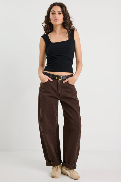 Woman wearing a black top and brown pants on a white background