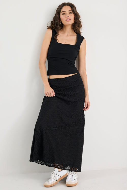 Woman wearing a black sleeveless top and long skirt on a white background