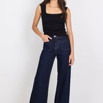 Woman wearing dark blue jeans and a black top on a white background