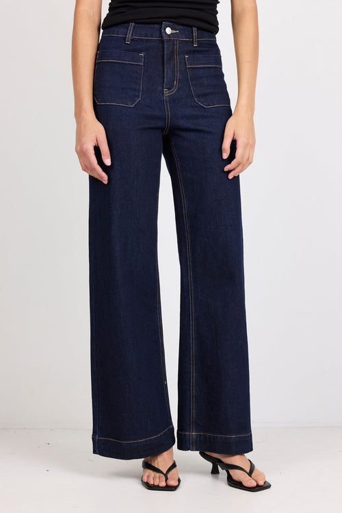 Person wearing dark blue wide-leg jeans on a white background