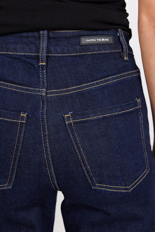 Close-up of dark blue jeans with a brand label on a white background