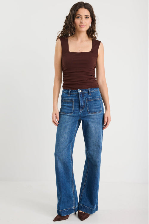 Woman wearing a brown ruched top and blue jeans