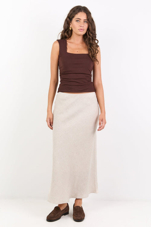 Woman wearing a brown top and beige skirt on a white background