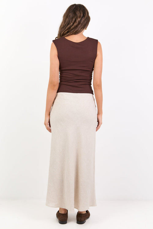 Woman wearing a brown top and beige skirt on a white background