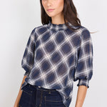 Woman wearing a blue plaid shirt and dark jeans on a white background