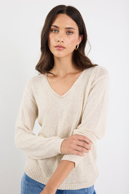 Woman wearing a beige sweater against a white background