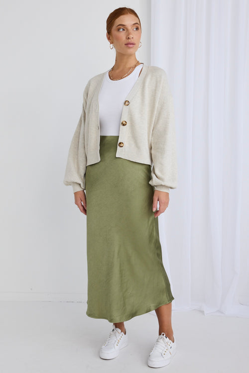 Model wears a oat knit with a green satin skirt