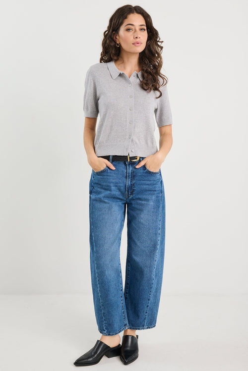 Woman wearing a grey knit and blue jeans on a white background