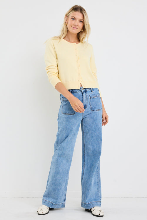 model wears a yellow cardigan with light blue jeans