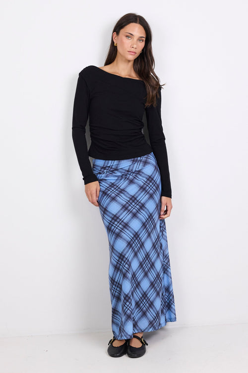 Woman wearing a black top and blue plaid skirt on a white background