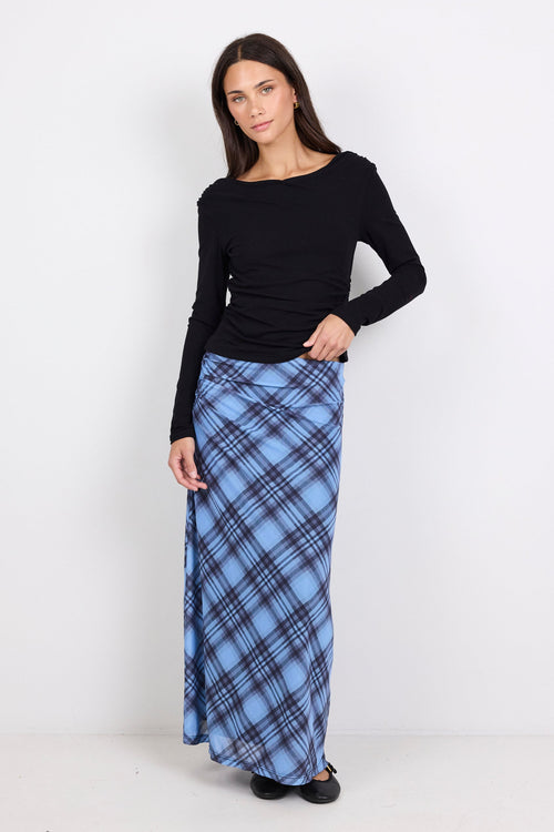 Woman wearing a black top and blue plaid skirt on a white background