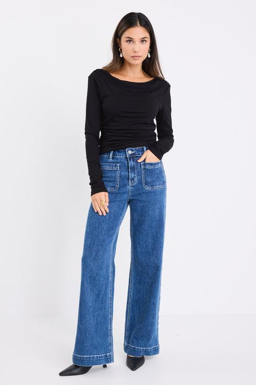 model wears a black long sleeve top with blue jeans